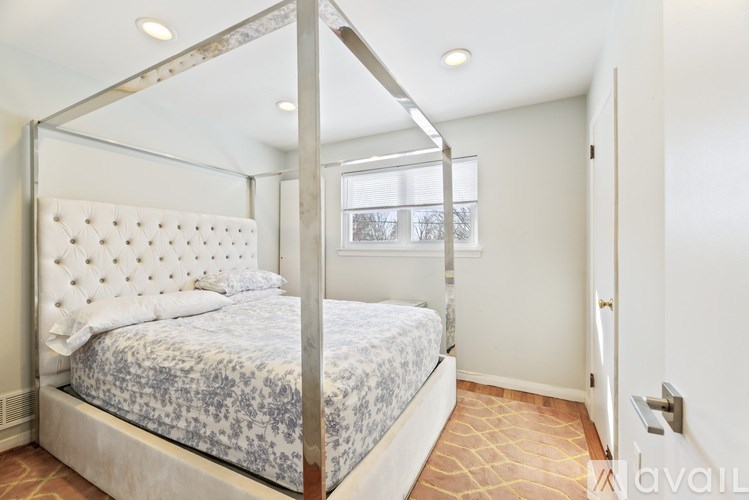 A bed with a white headboard and a blue and white patterned comforter sits in a room with a four poster frame.