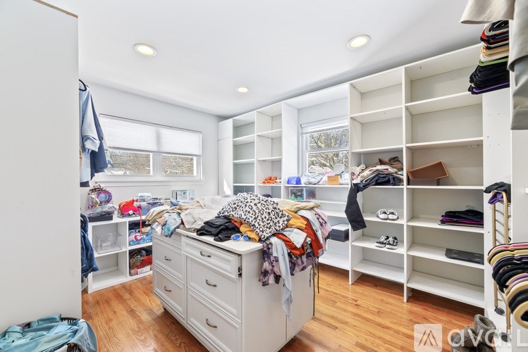 A room with a bed, shelves, and clothes.
