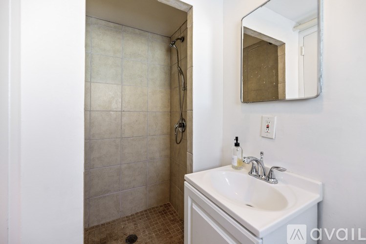 A bathroom with a sink, mirror, and tiled shower.