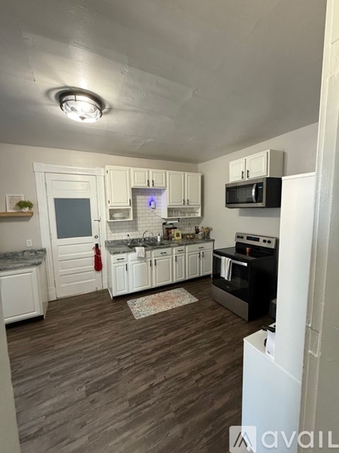 A kitchen with white cabinets and a black stove top oven.