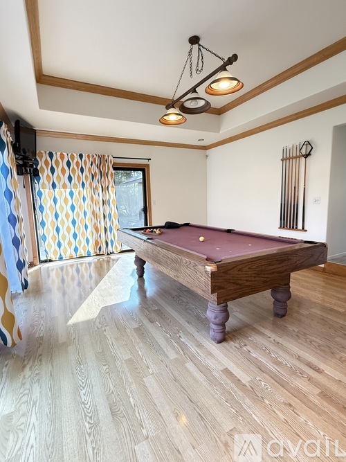 A room with a pool table and a television.