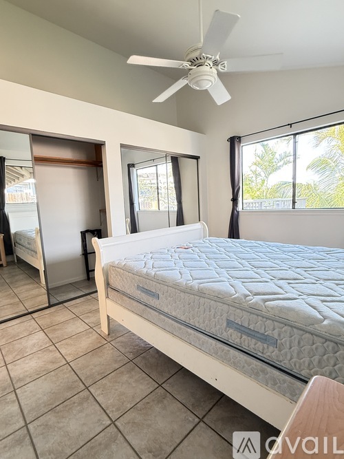 A bedroom with a large bed and a ceiling fan.