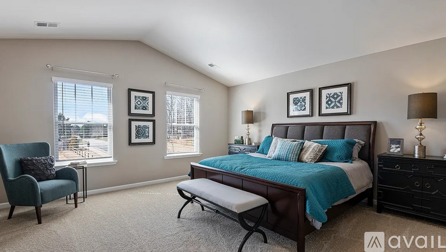 A bedroom with a bed, chair, and pictures on the wall.