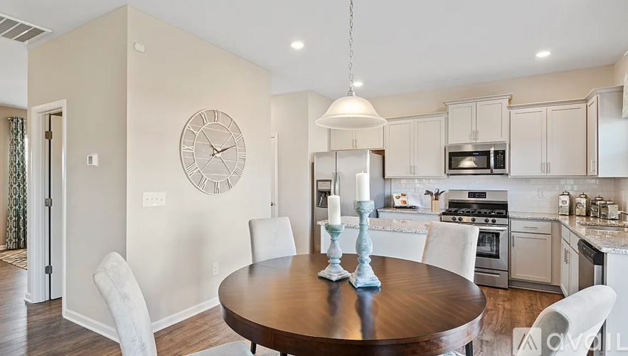 A kitchen with a table and chairs and a clock on the wall.