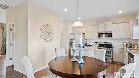 A kitchen with a table and chairs and a clock on the wall.