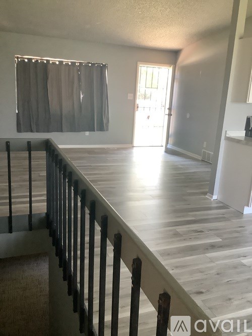 A room with a wooden floor and a staircase leading to the second floor.