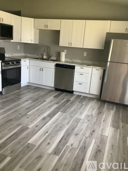 A kitchen with white cabinets and a wooden floor.