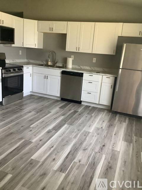 A kitchen with white cabinets and a wooden floor.