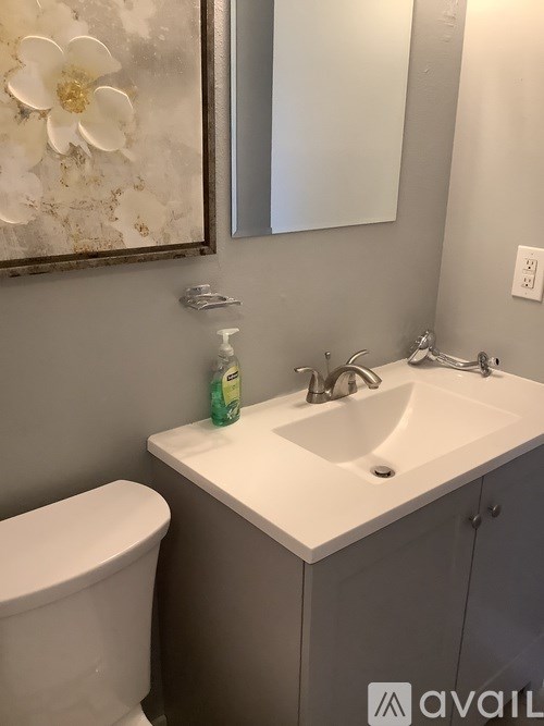 A white sink with a green bottle of soap on it.