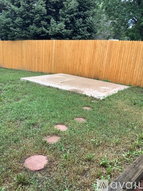 A wooden fence with a small patch of dirt in the middle of a grassy area.