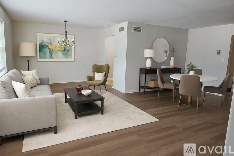 A living room with a grey couch, a coffee table, a lamp, a chair, a dining table, and a painting on the wall.