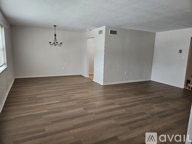 A room with wooden flooring and a chandelier hanging from the ceiling.