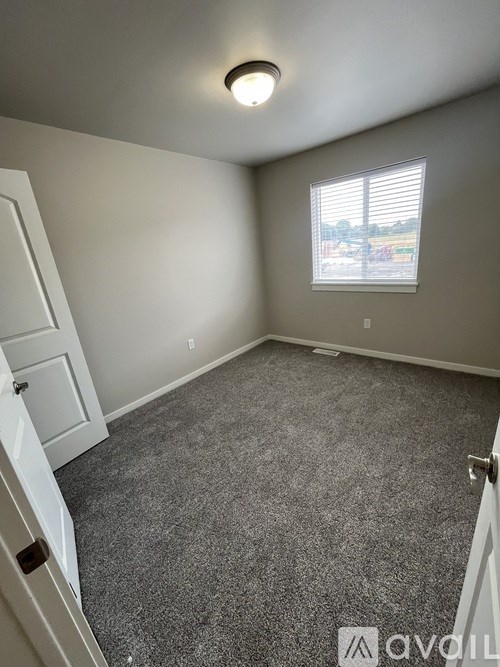 A room with a carpeted floor and a window with blinds.