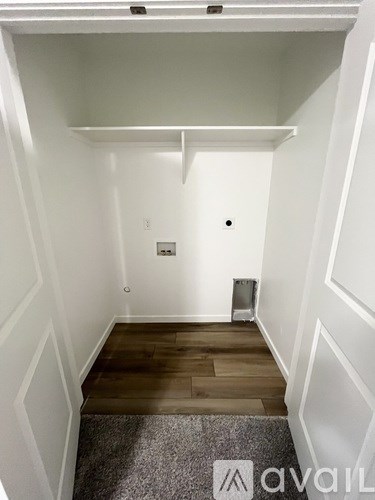 A room with white walls and wooden flooring with a carpet on the floor.