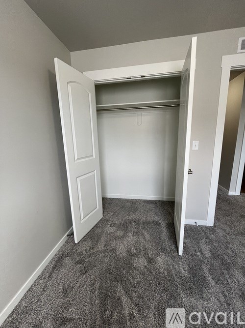 A room with a white door and a grey carpet.