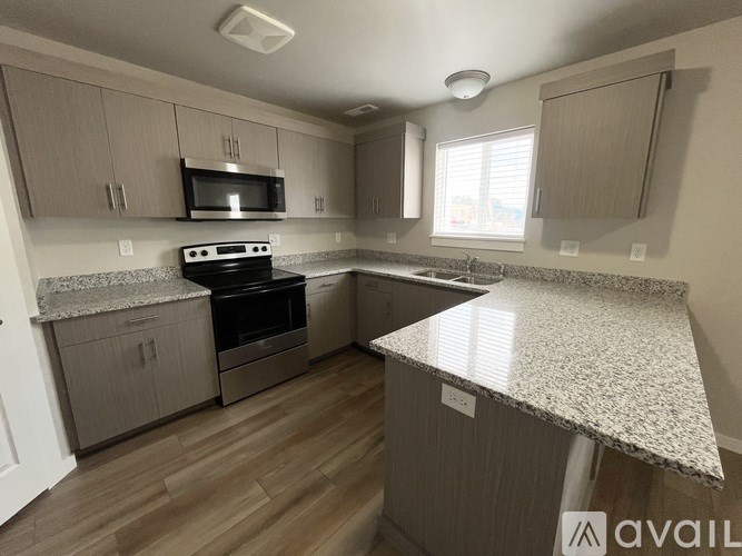 A kitchen with a granite countertop and wooden flooring.