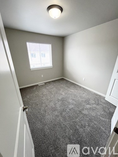 A room with a carpeted floor and a window with blinds.