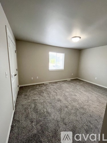 A room with a carpeted floor and a window with blinds.
