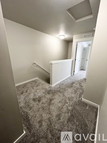 A hallway with a carpeted floor and a staircase leading to another room.