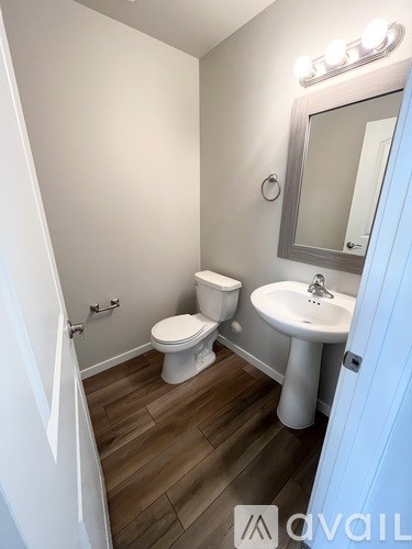 A bathroom with a toilet, sink, and mirror.