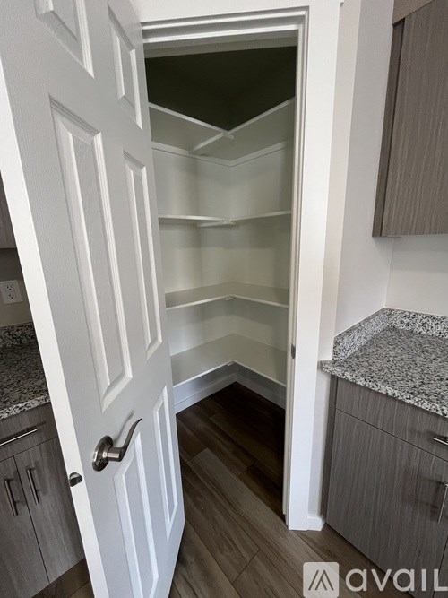 A white door is open to a kitchen with a granite countertop.