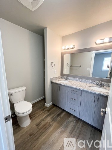 A bathroom with a toilet, sink, and mirror.