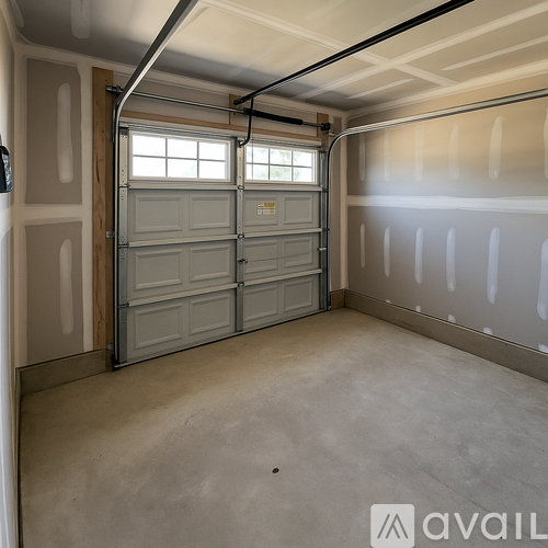 A spacious garage with a closed grey door and a wall-mounted shelf.