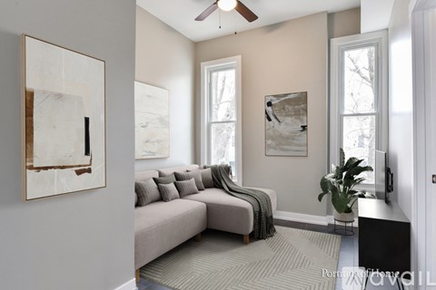A living room with a grey couch and a painting on the wall.