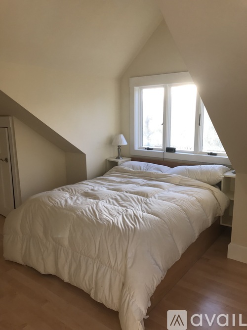 A bedroom with a bed, a nightstand, and a window.