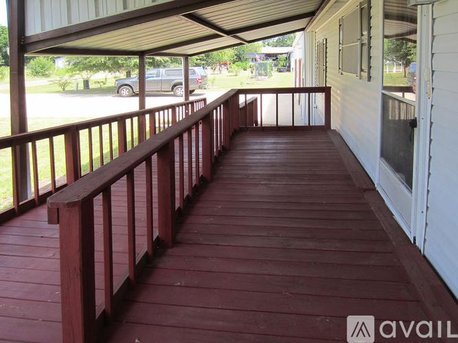 A wooden deck with a metal railing and a white house.