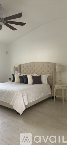 A white couch with a pillow and a dog on it.