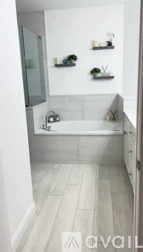 A bathroom with a tub, sink, and shelves with plants.
