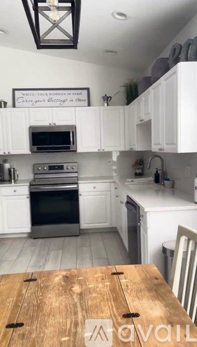 A kitchen with white cabinets and a wooden table.