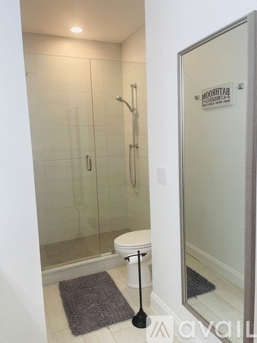 A bathroom with a toilet, a glass shower stall, and a glass door.