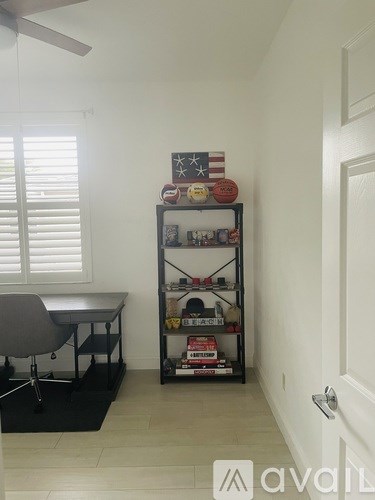 A room with a chair, a table, and a shelf with various items on it.