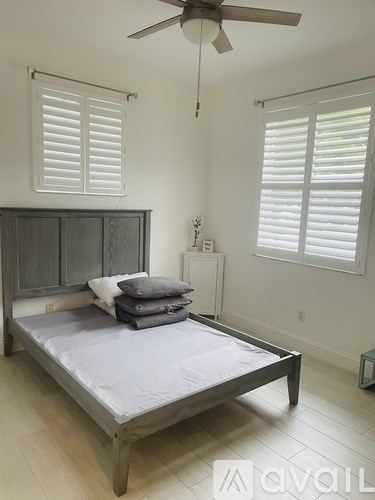 A bedroom with a bed, nightstand, and window with blinds.