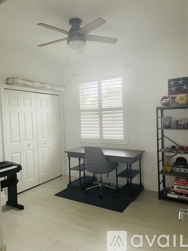 A room with a desk, chair, and shelves.
