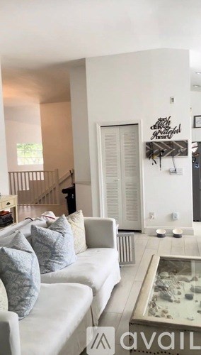 A living room with a white couch and a glass coffee table.