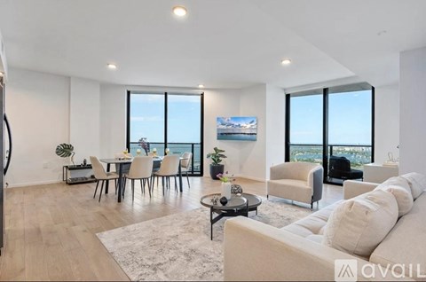 A living room with a white couch and a dining table with chairs.