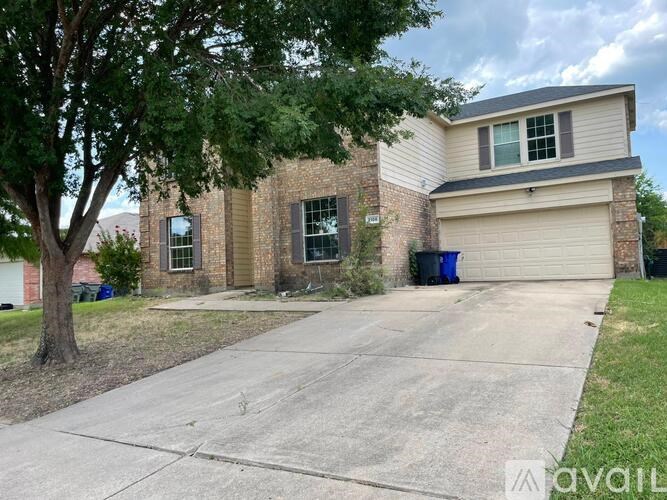 A house with a driveway and a tree in front.