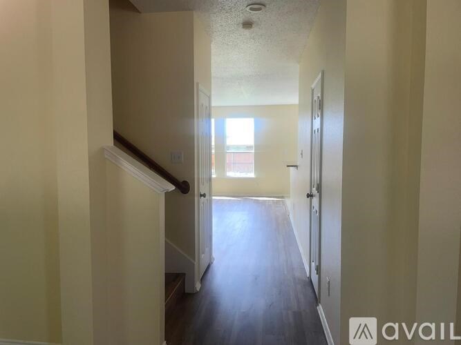 A hallway with a staircase leading to a door on the right.