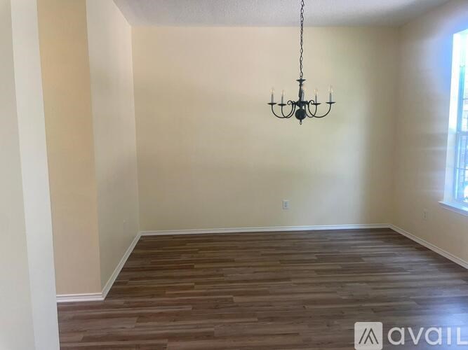 A room with wooden flooring and a chandelier hanging from the ceiling.