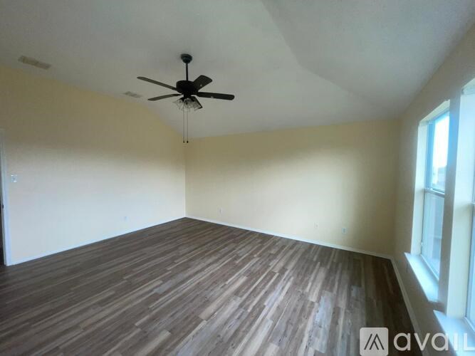 A room with wooden flooring and a ceiling fan.