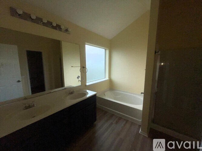 A bathroom with a tub, sink, and mirror.