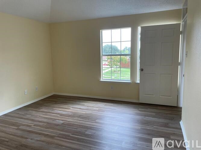 A room with wooden flooring and a white door.
