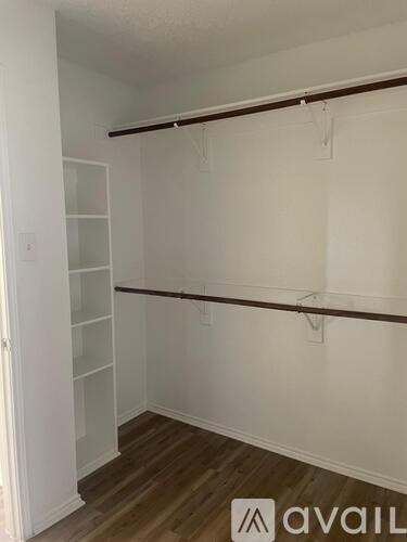A white room with a wooden floor and a wall-mounted shelf.