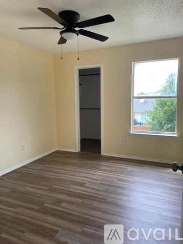 A room with a ceiling fan and a door leading to another room.