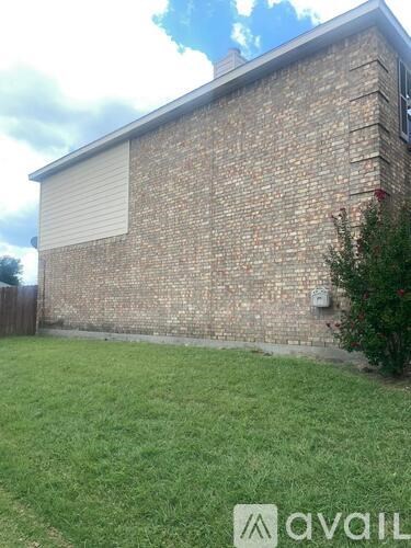 A brick house with a white roller shutter door and a green lawn in front.