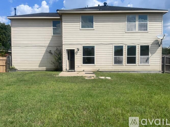 A house with a satellite dish on the roof and a fence in the front yard.