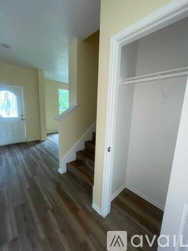 A hallway with a staircase and a door on the left.